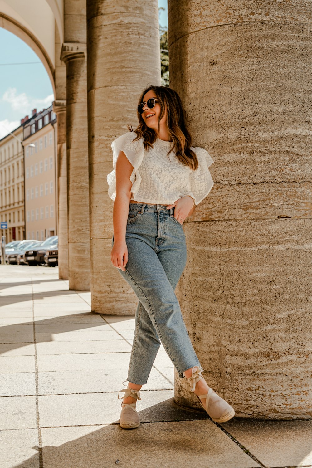 woman in white tank top and blue denim jeans standing on brown concrete floor during daytime