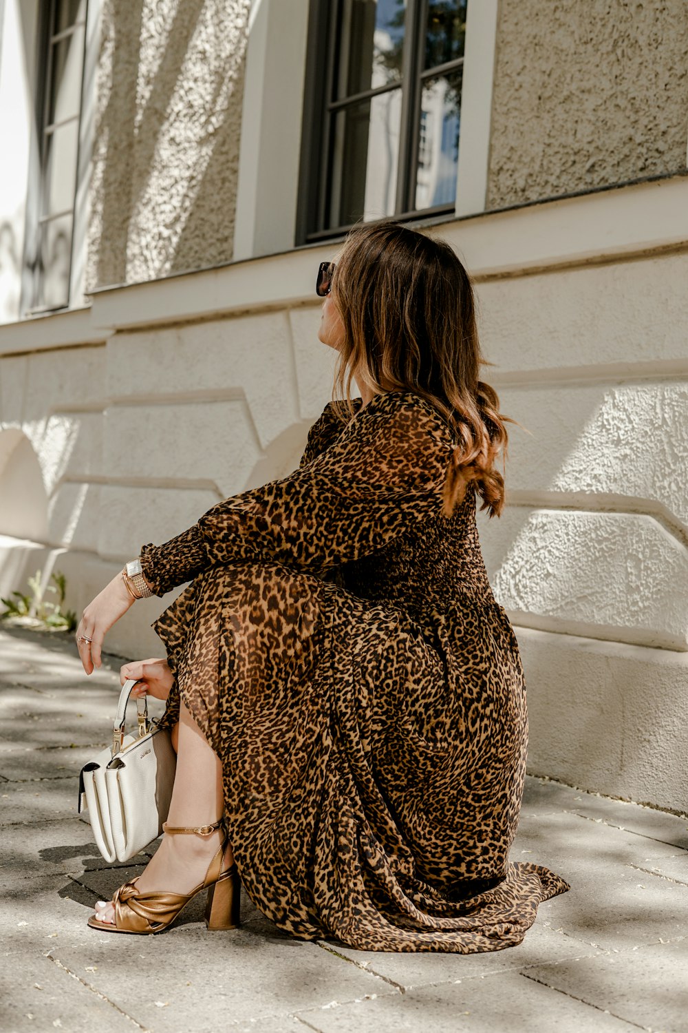 woman in brown and black leopard print dress holding white leather handbag