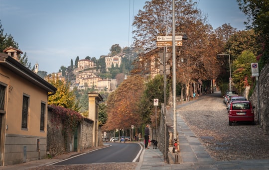 gray concrete road with cars parked on side during daytime in Bergamo Italy