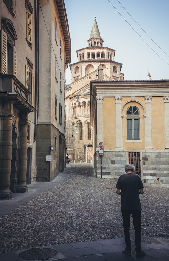 man in black coat standing in front of brown concrete building during daytime in Palazzo della Ragione Italy