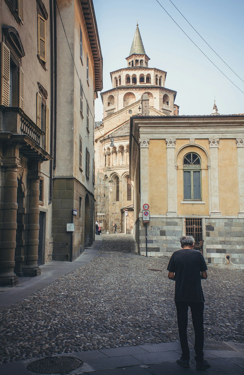 man in black coat standing in front of brown concrete building during daytime