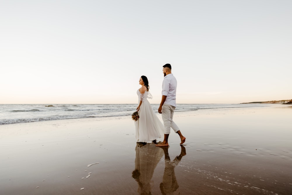 Hombre y mujer tomados de la mano mientras caminan por la playa durante el día