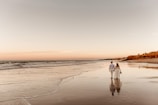 A couple walking hand-in-hand along a curved shoreline with deep navy twilight sky above