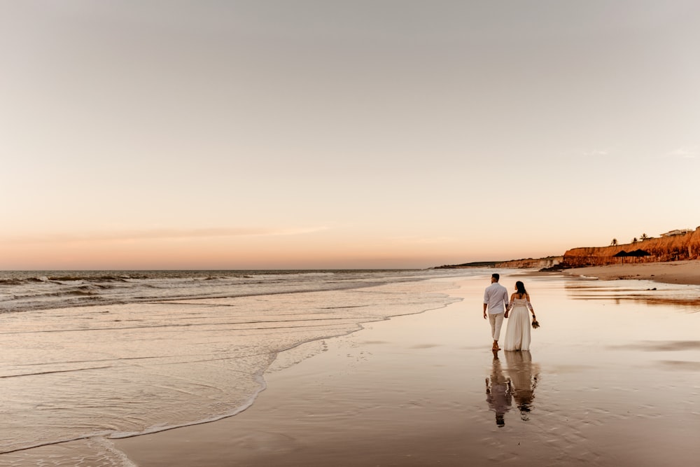 Frau in weißem Kleid geht bei Sonnenuntergang am Strand spazieren