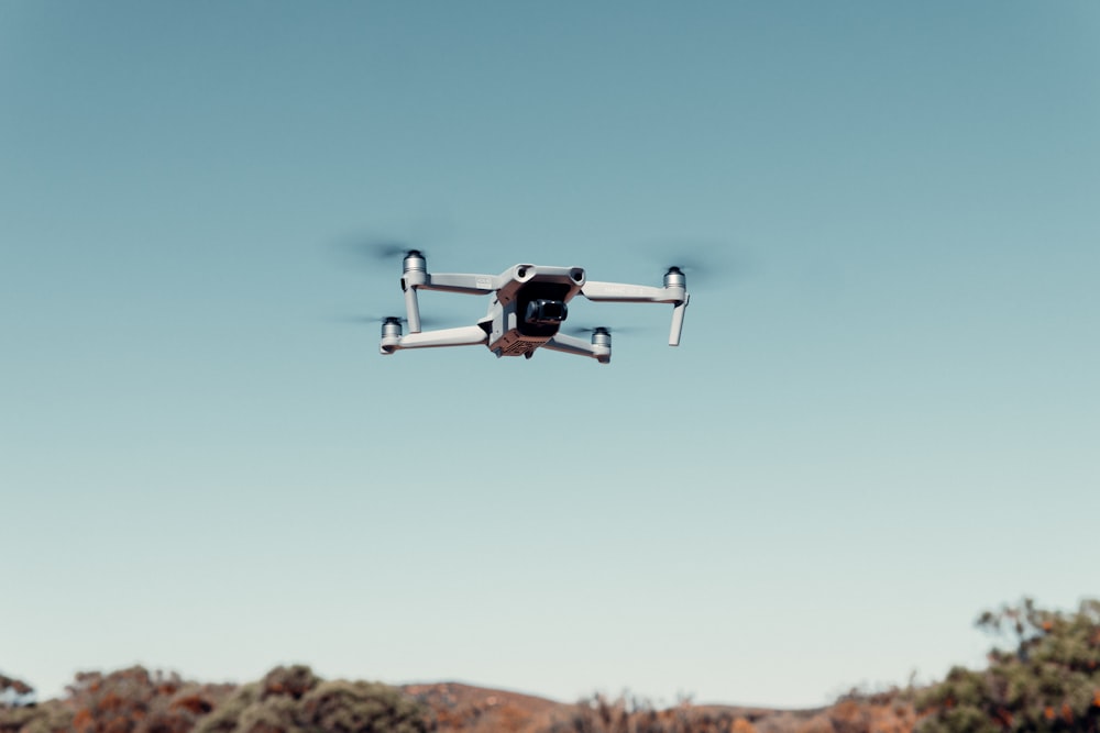 drone preto e branco voando no céu durante o dia