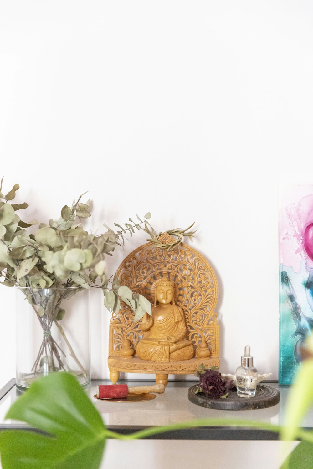 a table topped with a buddha statue next to a vase of flowers