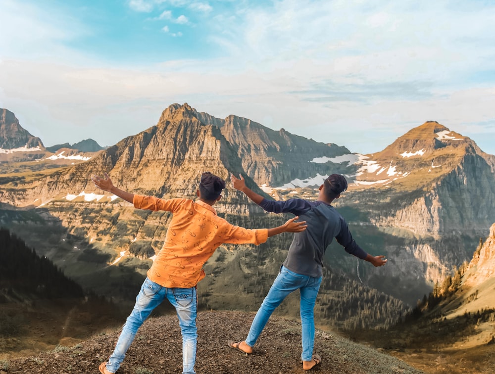 man in brown jacket and blue denim jeans standing on rock formation during daytime