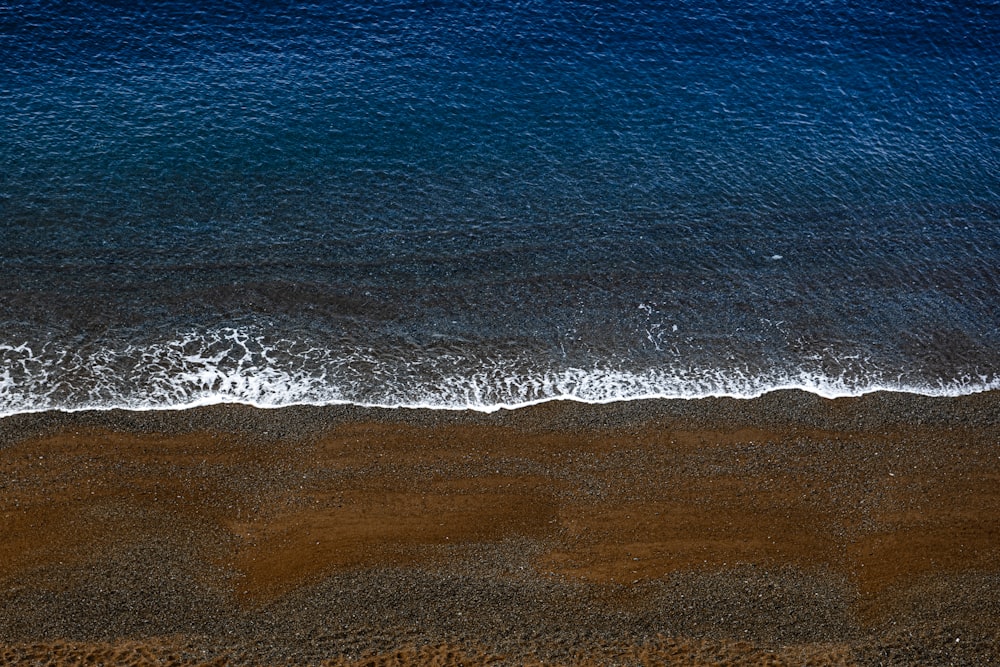 blue ocean waves on brown sand during daytime