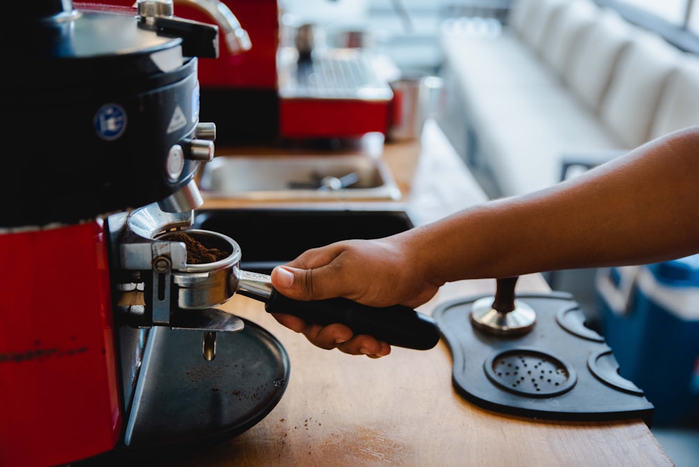 person holding silver and black coffee maker