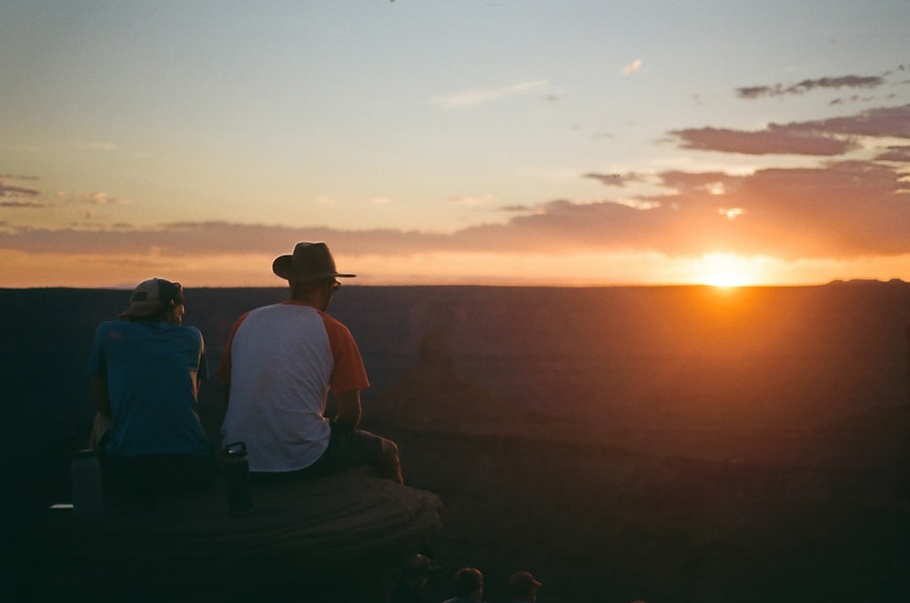 man in white t-shirt sitting on bench during sunset