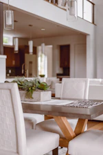 A sleek modern dining table set with soft natural light highlighting its aluminum frame.