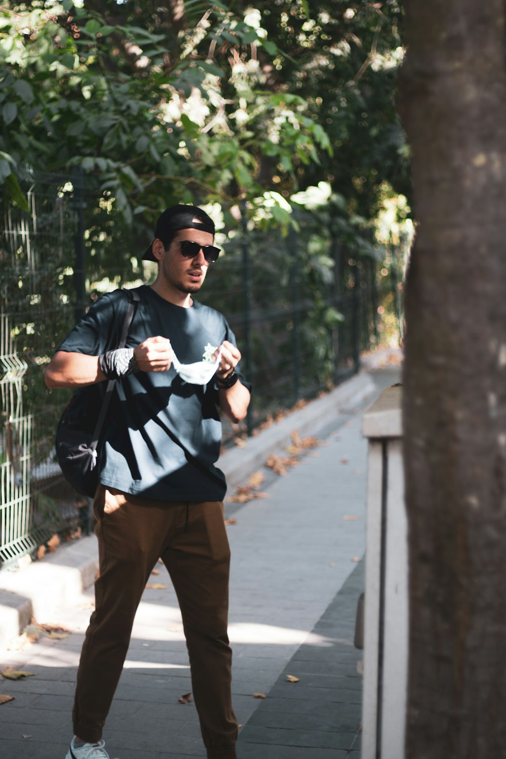 man in black and white long sleeve shirt and brown pants standing beside brown tree during