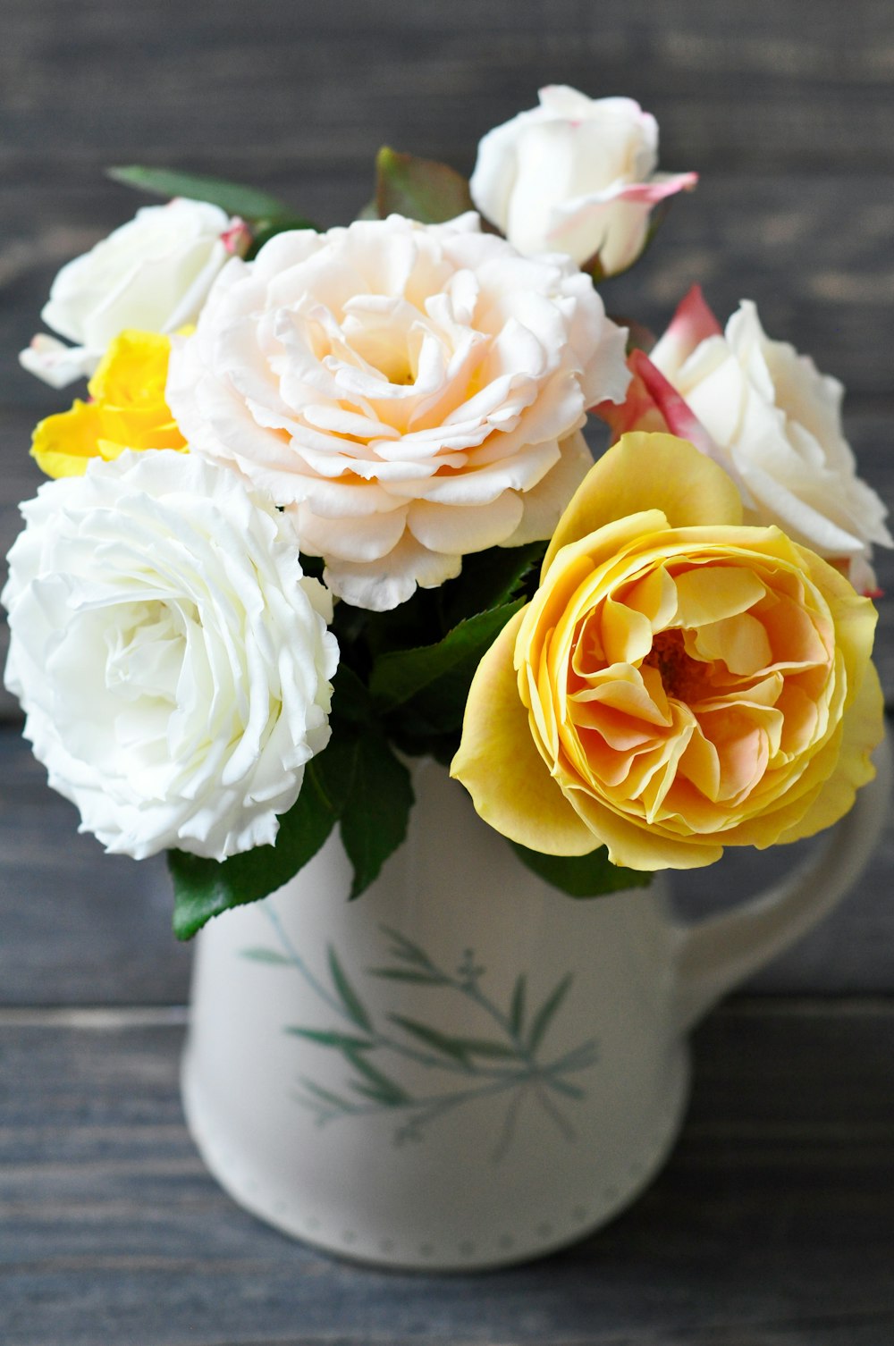 white and yellow roses in white ceramic vase