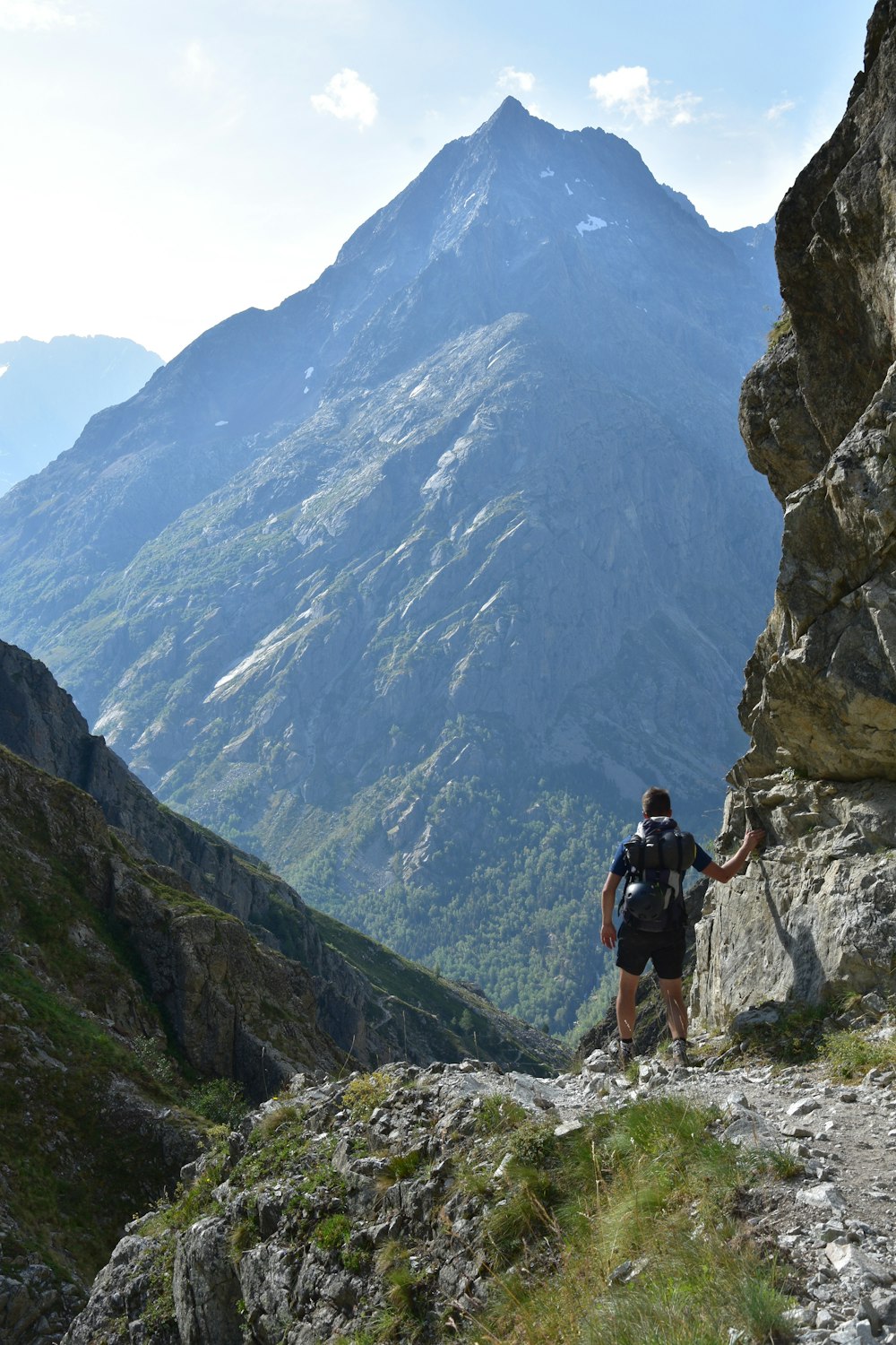 Mann in schwarzem Hemd und schwarzen Shorts geht tagsüber auf dem Rocky Mountain spazieren