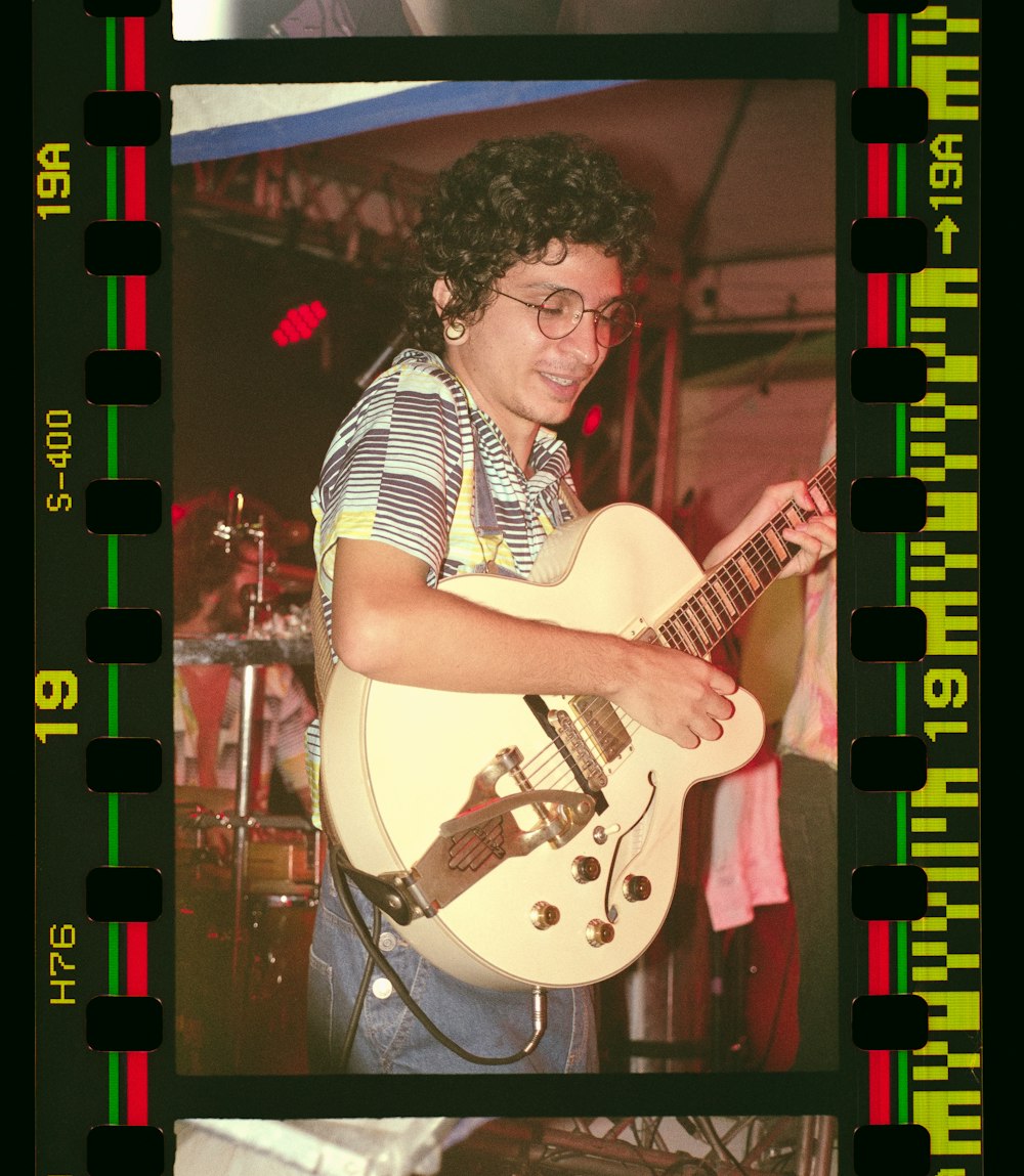 man in white and blue striped button up shirt playing white electric guitar