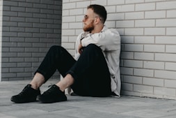 man in white dress shirt and black pants sitting on floor