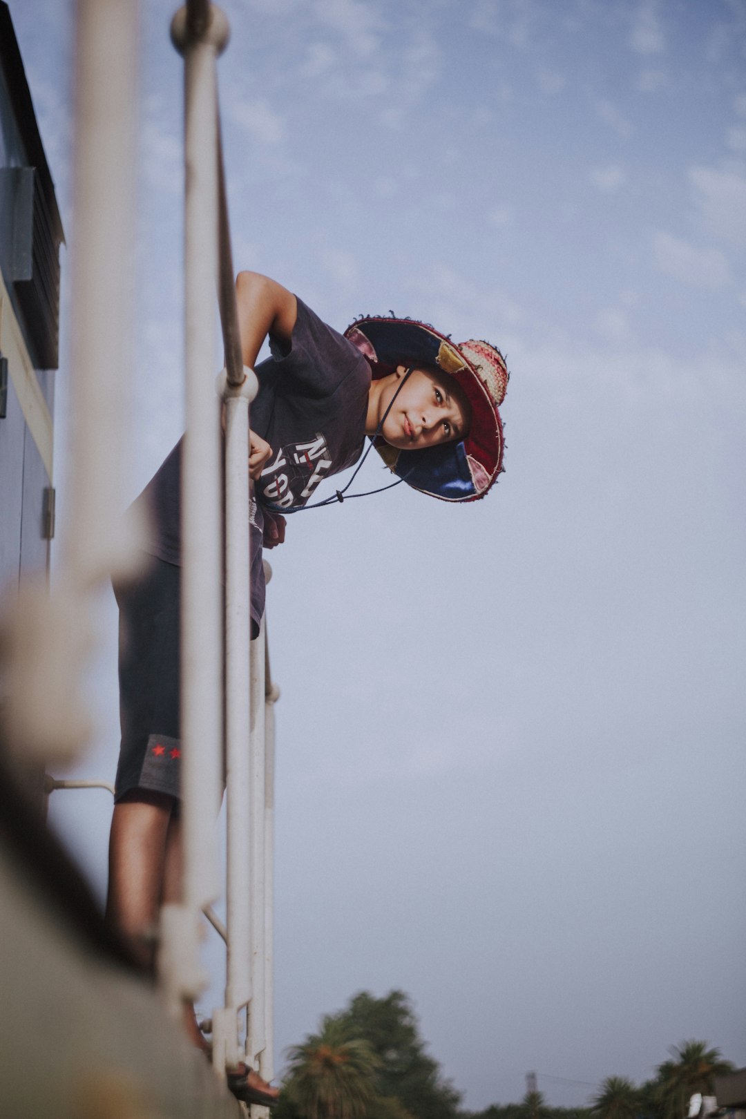 man in black tank top and black shorts climbing on white metal pole during daytime