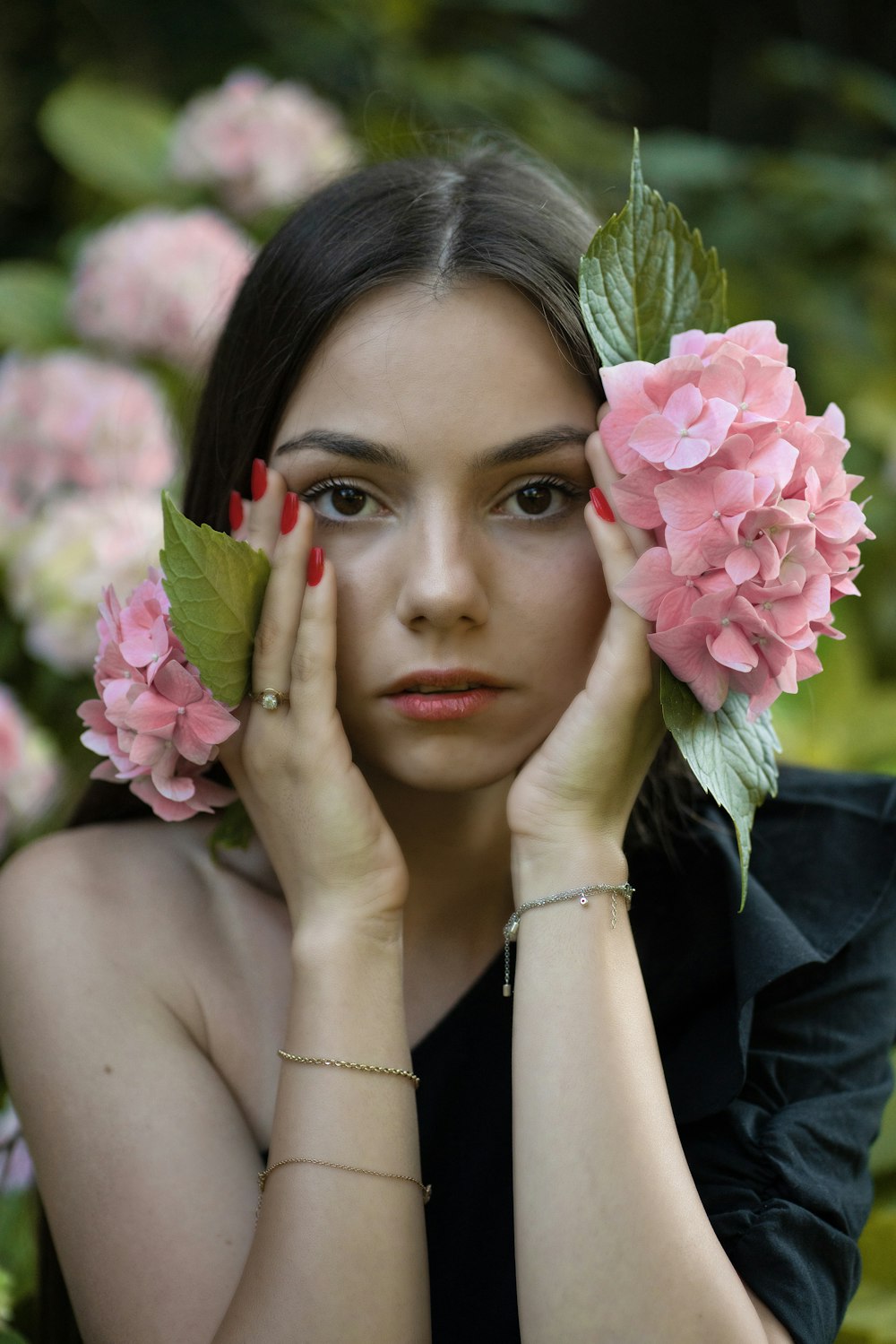 woman in black shirt holding pink flower