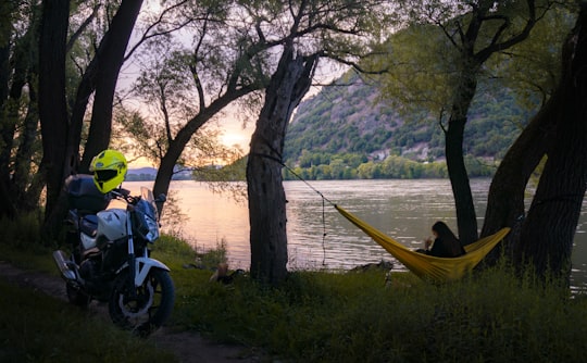 man and woman sitting on bench near lake during daytime in Visegrád Hungary