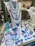 A display of various colorful jewelry pieces, including necklaces, bracelets, rings, and earrings, featuring shades of blue, purple, and green. The items are elegantly arranged on a mannequin and a showcase counter, highlighting the intricate designs and vibrant hues.