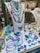 A display of various colorful jewelry pieces, including necklaces, bracelets, rings, and earrings, featuring shades of blue, purple, and green. The items are elegantly arranged on a mannequin and a showcase counter, highlighting the intricate designs and vibrant hues.