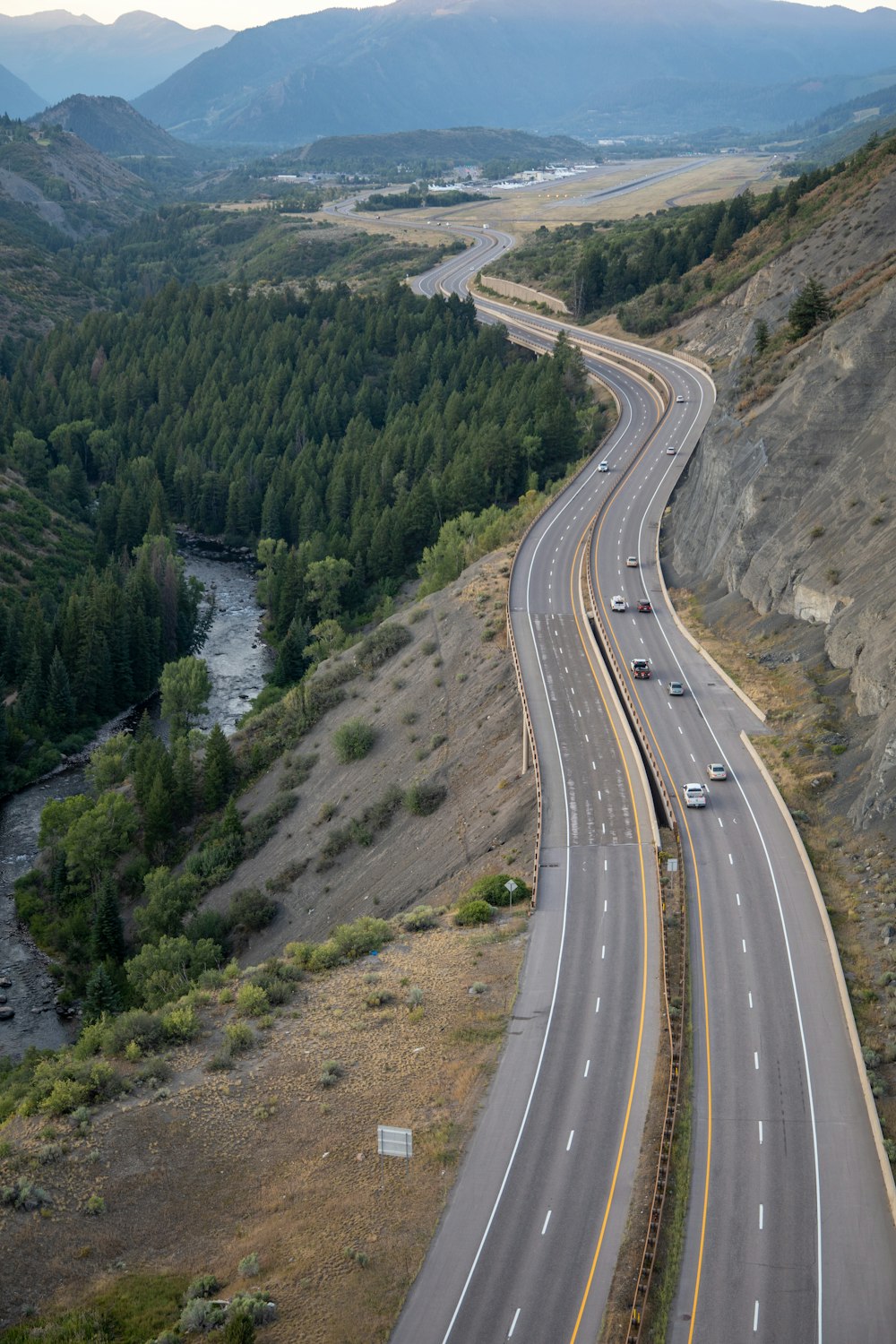 aerial view of road between green trees during daytime