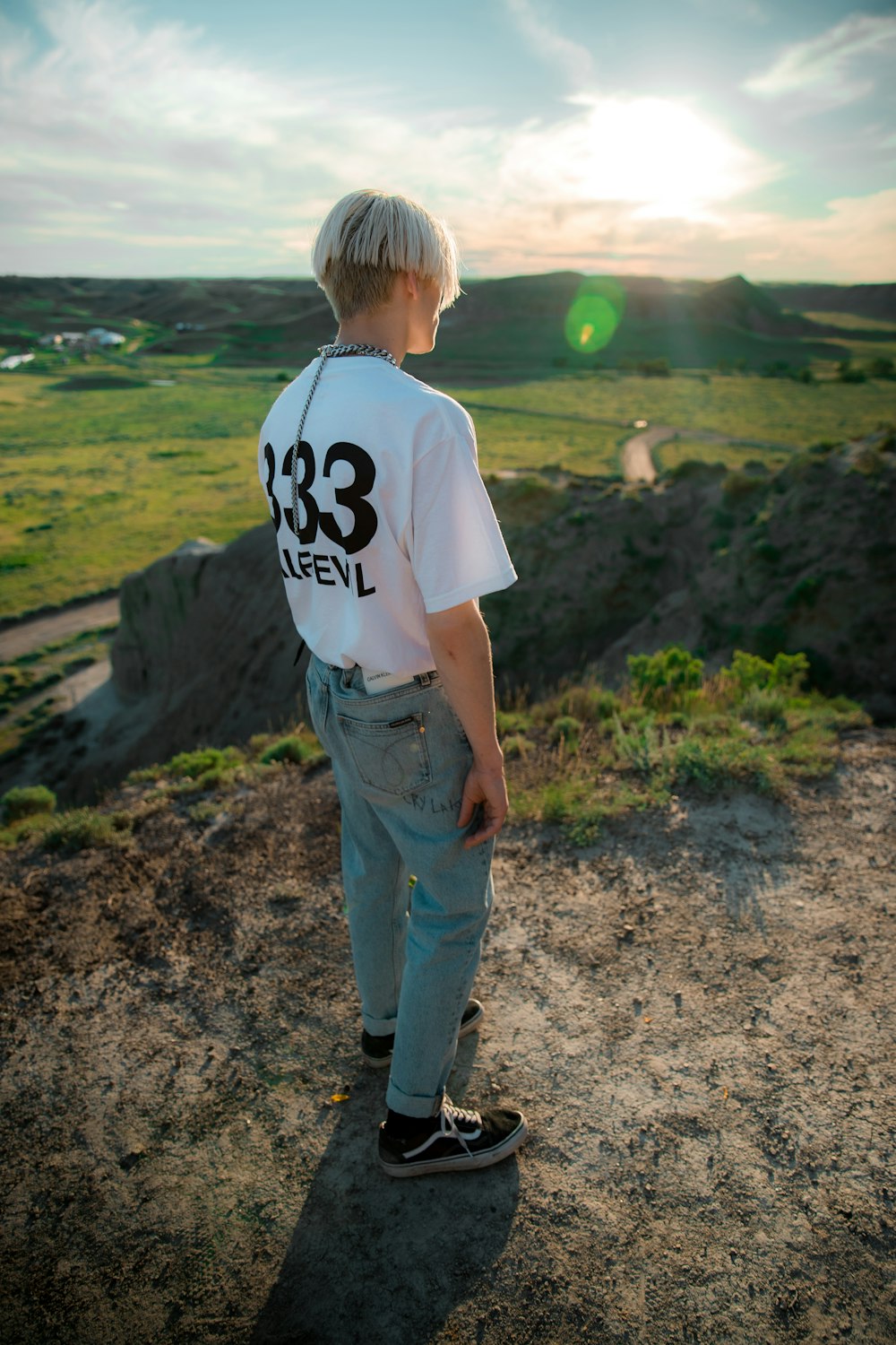 boy in white t-shirt and blue denim jeans standing on dirt ground during daytime