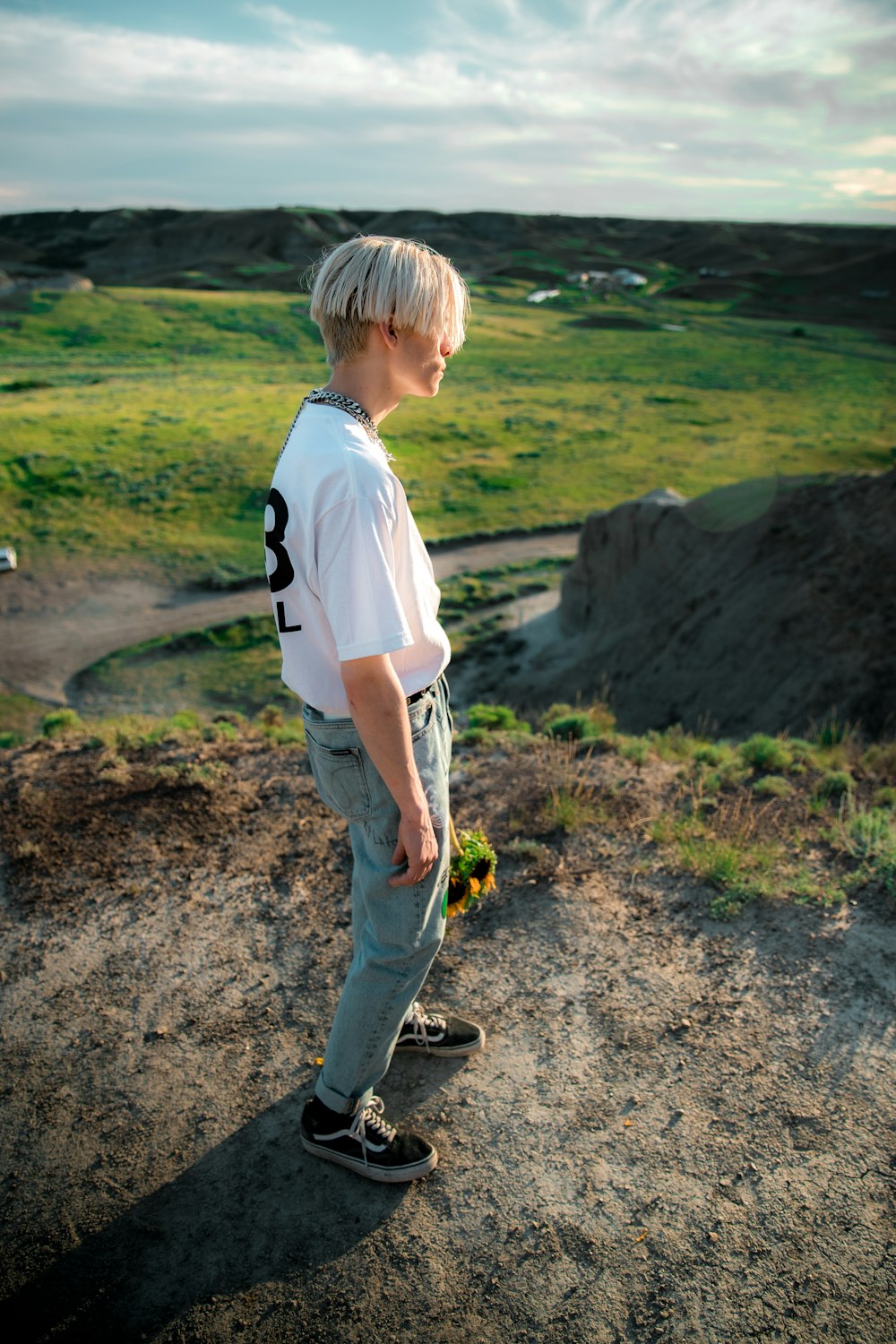 boy in white shirt and gray pants with black backpack walking on dirt road during daytime
