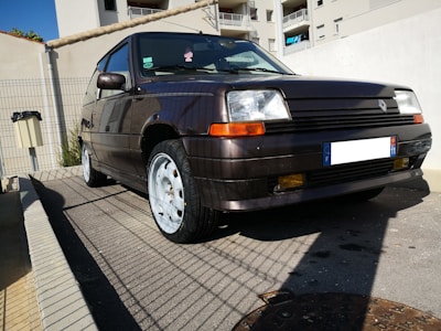A reliable older hatchback parked neatly beside a charcoal brick wall, highlighting its clean lines.