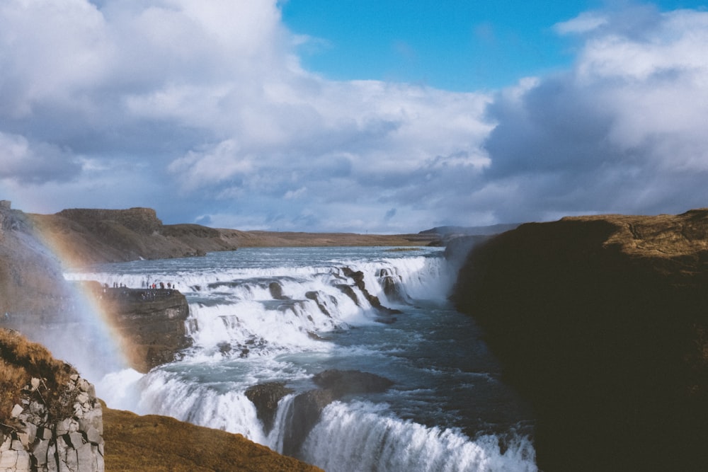 water falls under blue sky and white clouds during daytime