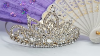 Close-up of dazzling bling lashes adorned with tiny diamonds, set against a rich purple and gold background with crown motifs.