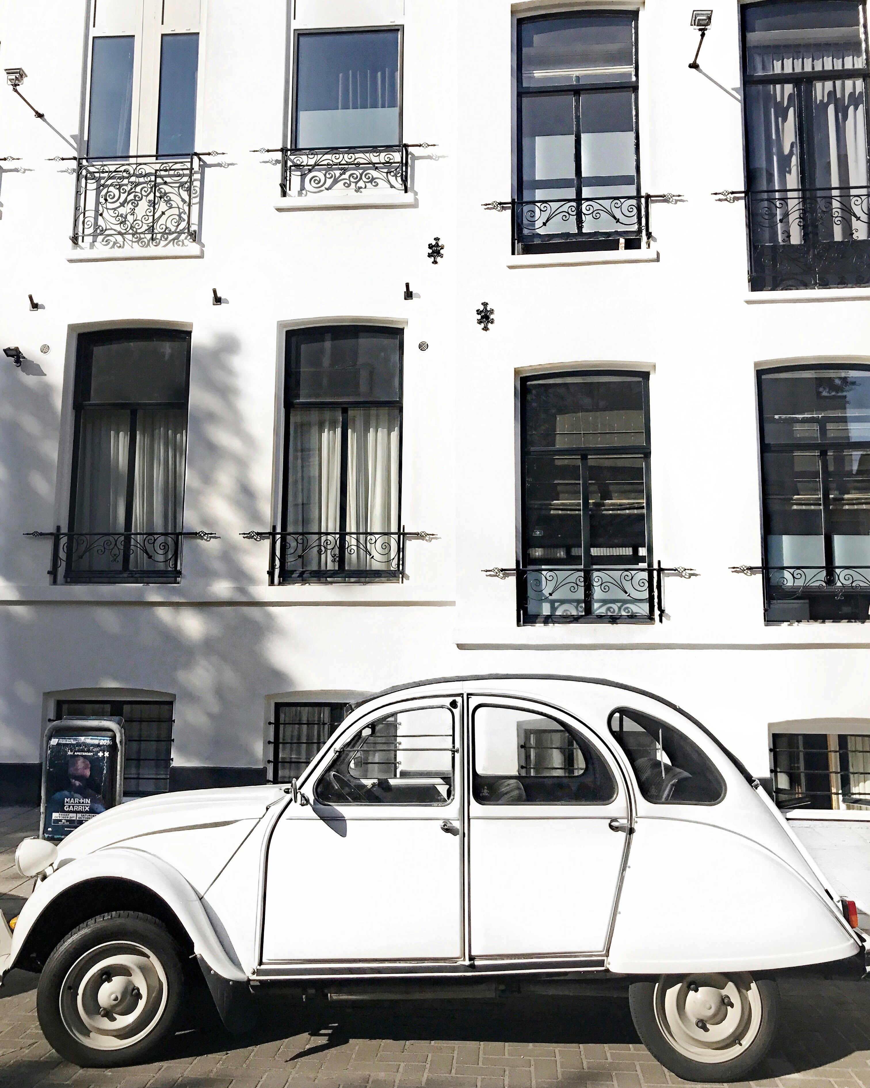 Coche blanco aparcado junto a un edificio de hormigón blanco durante el día
