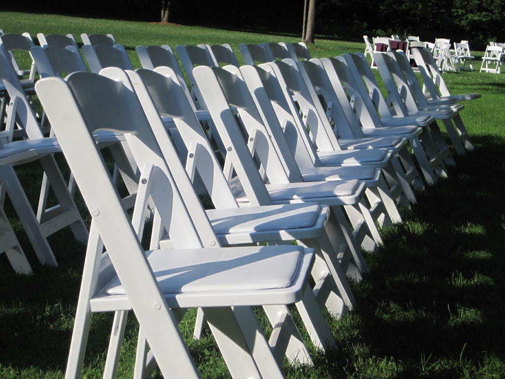 sillas plegables blancas en campo de hierba verde