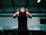 man in black tank top raising his hands