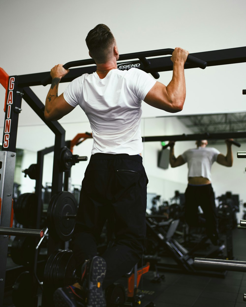 man in white crew neck t-shirt and black pants holding black exercise equipment