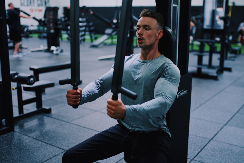 man in gray long sleeve shirt and black pants holding black metal bar