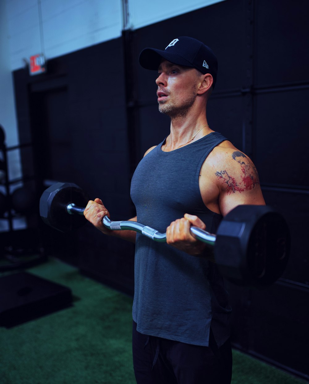 man in gray tank top holding black dumbbell