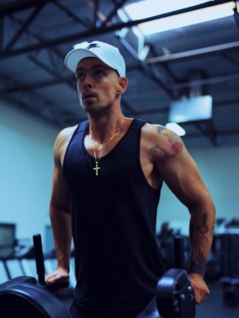 A dynamic shot of Kieron Rada mid-workout, sweat glistening, with a subtle cross necklace visible.