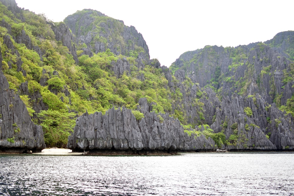 green and gray mountain beside body of water during daytime