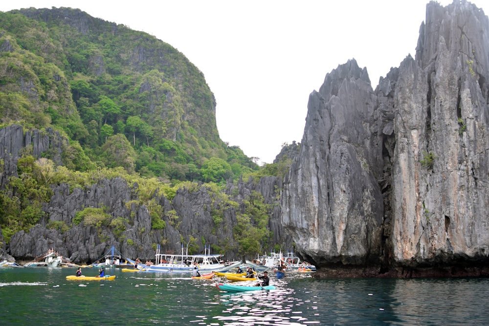 white and blue boat on body of water near gray rock mountain during daytime