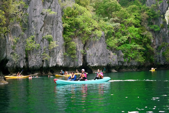 people riding on blue kayak on river during daytime in Palawan Philippines