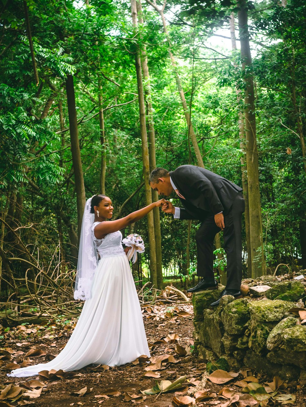 man and woman holding hands while walking on forest during daytime