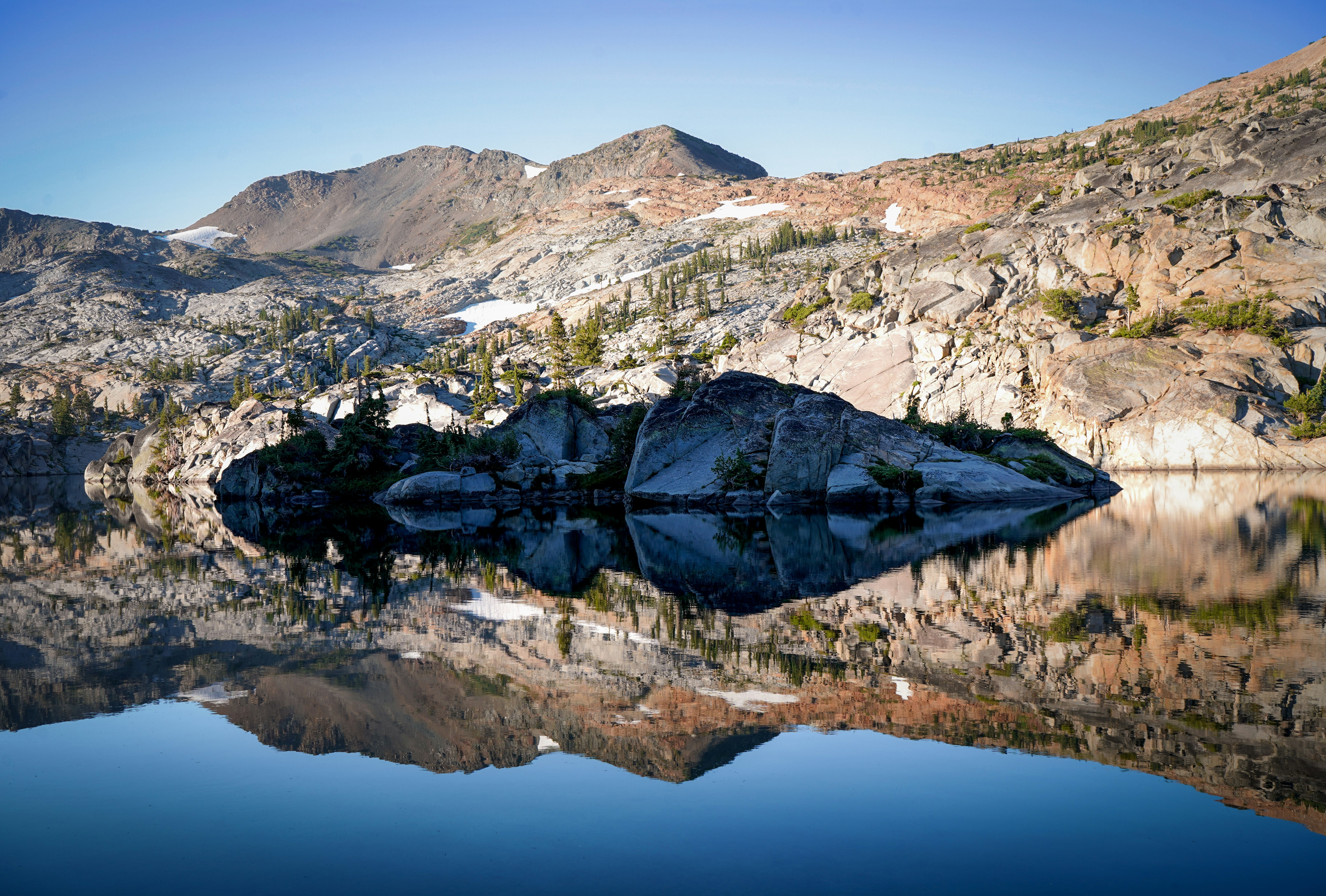 green and white mountain near body of water during daytime