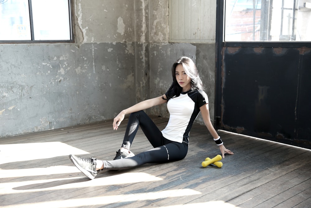 woman in black tank top and black leggings sitting on floor