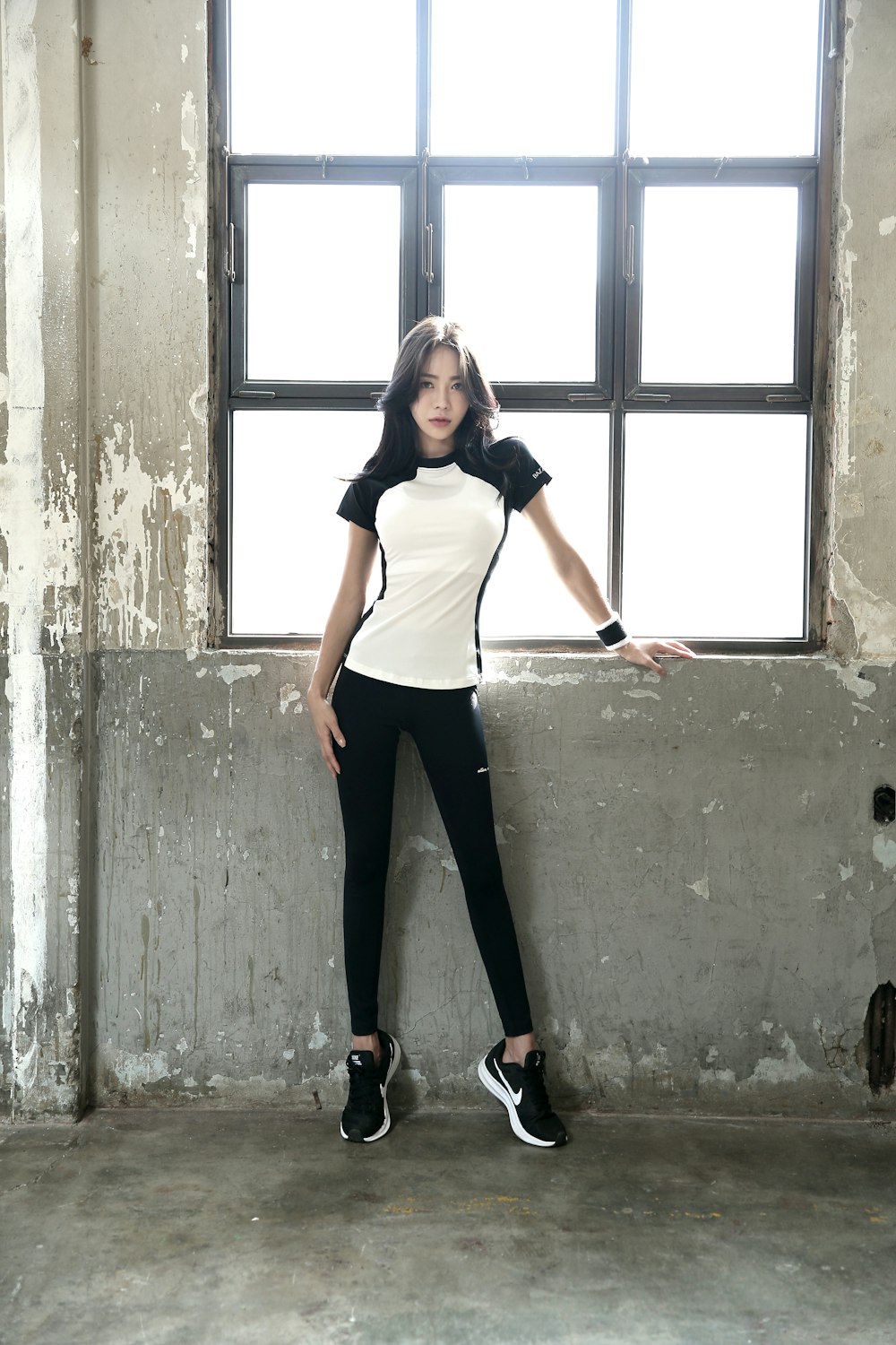 woman in white tank top and black pants standing near window during daytime