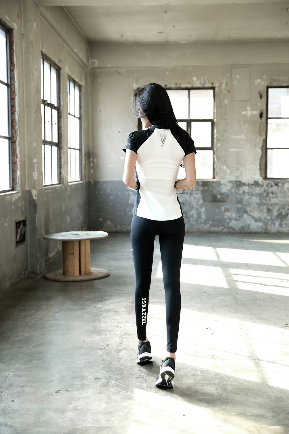 woman in white shirt and black pants standing near gray concrete wall during daytime