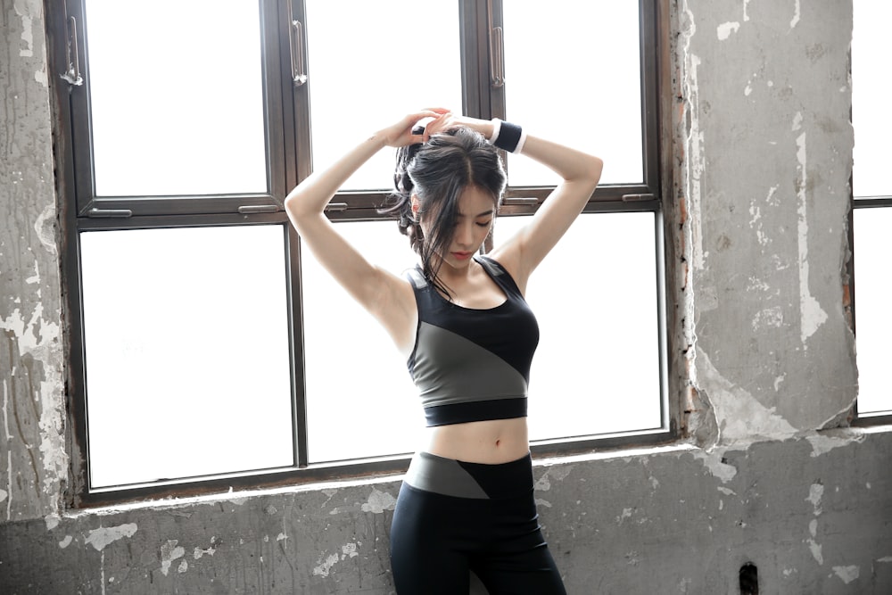 woman in black tank top and black leggings standing near window during daytime