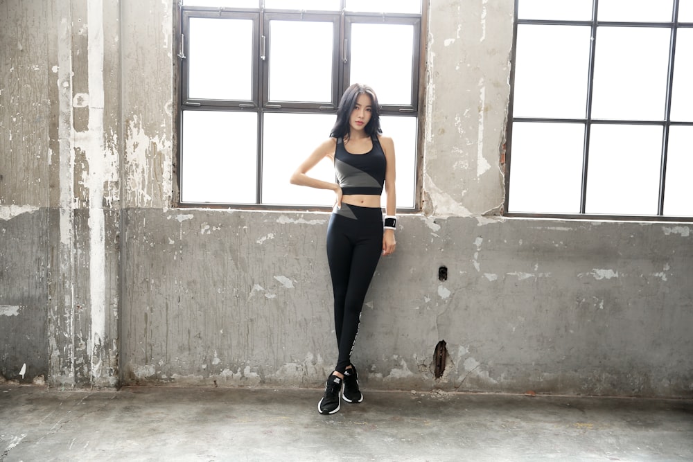 woman in black tank top and black pants standing beside window during daytime