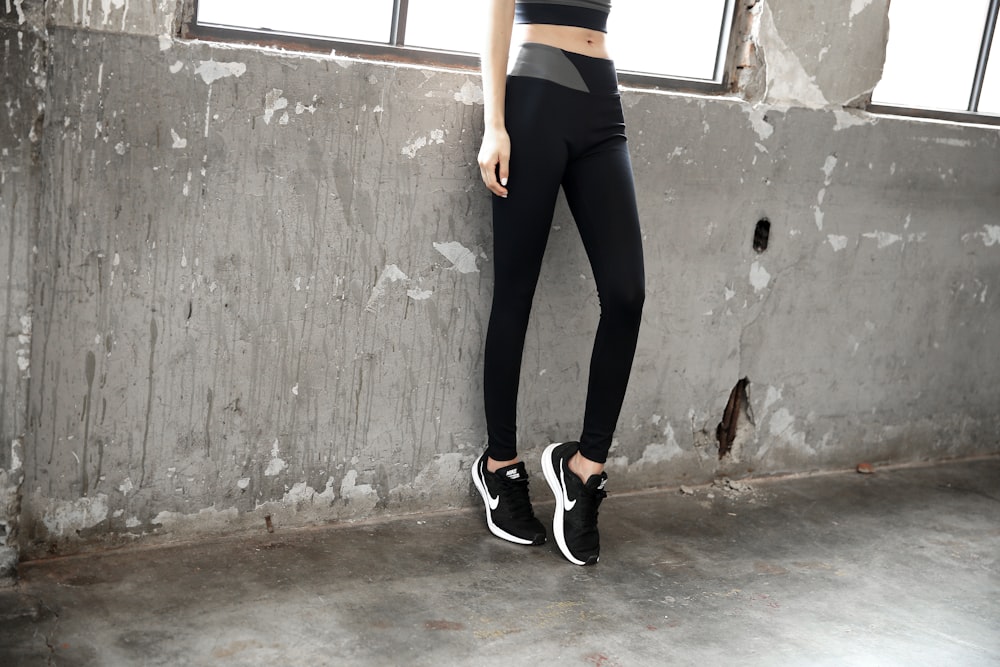 mulher em leggings pretas e tênis nike preto e branco