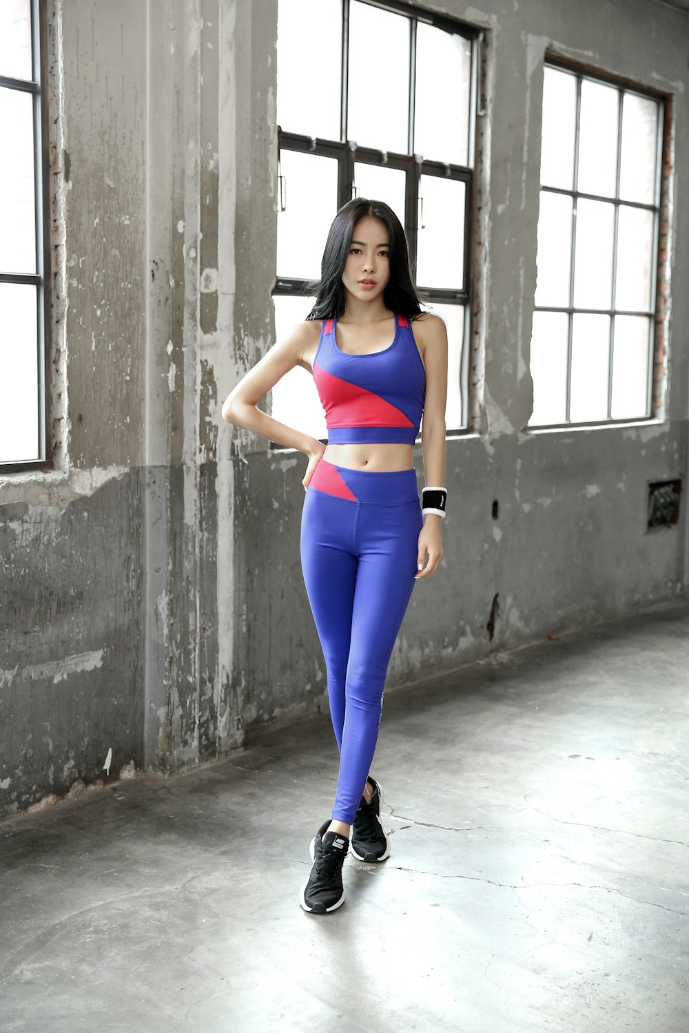 woman in blue and orange sports bra and blue leggings standing on hallway